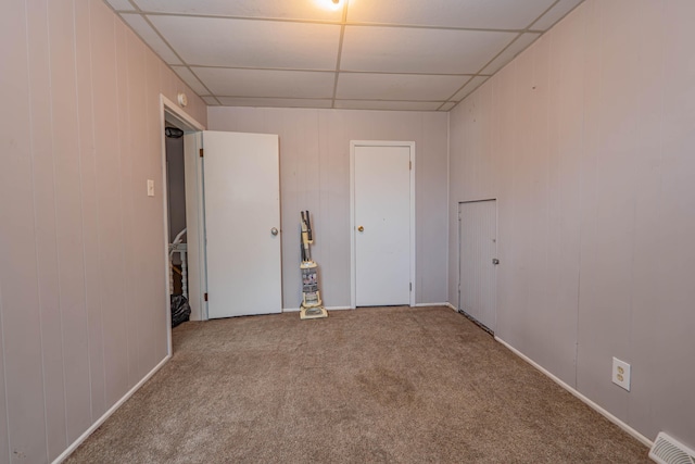 empty room featuring a drop ceiling and carpet flooring