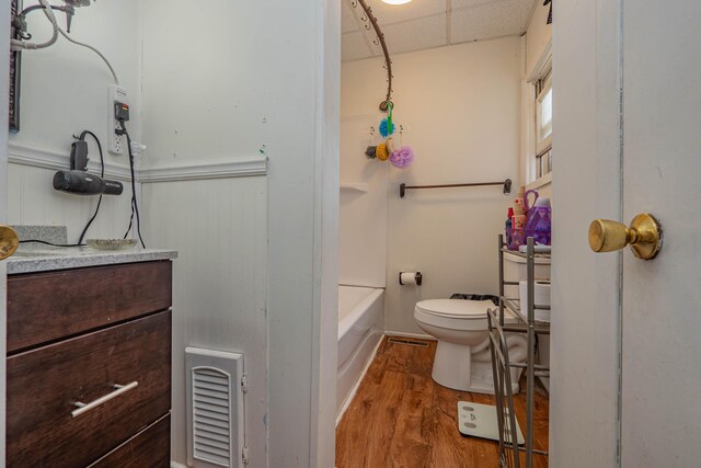 full bathroom with hardwood / wood-style floors, a paneled ceiling,  shower combination, toilet, and vanity