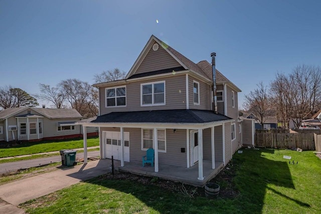 rear view of house with covered porch, a yard, and a garage