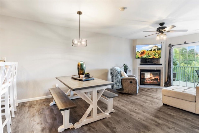 dining area featuring ceiling fan, a tile fireplace, and hardwood / wood-style floors