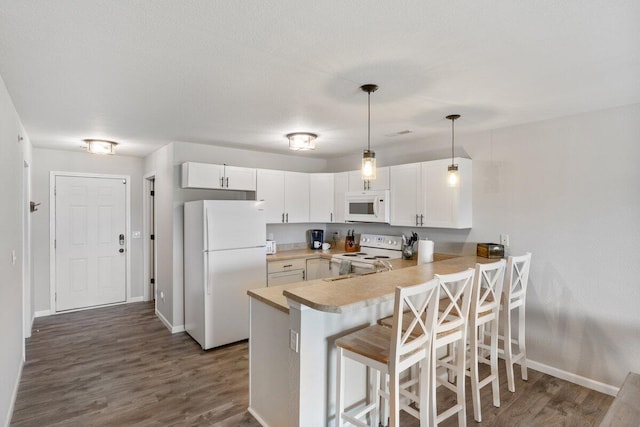 kitchen featuring white cabinets, white appliances, kitchen peninsula, and dark hardwood / wood-style floors