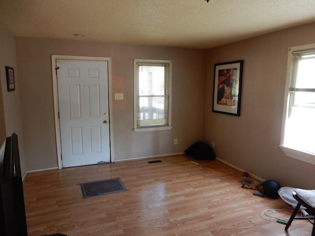 foyer with light wood-type flooring and a textured ceiling