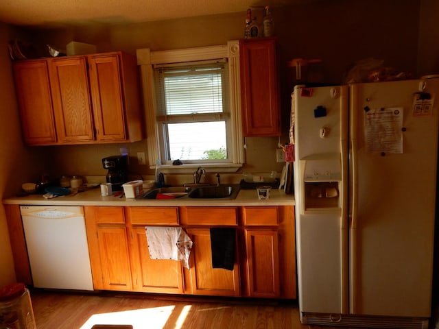 kitchen featuring white appliances, sink, and light hardwood / wood-style flooring