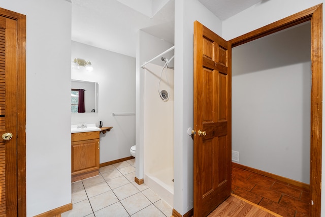 bathroom with tile patterned flooring, a shower, vanity, and toilet