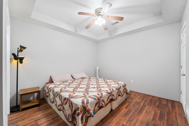 bedroom featuring ceiling fan, a raised ceiling, and dark hardwood / wood-style floors