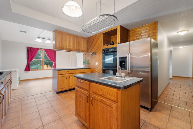 kitchen featuring stainless steel fridge, light tile patterned floors, sink, double oven, and a center island