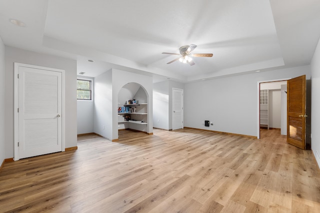 unfurnished bedroom with ceiling fan, light hardwood / wood-style flooring, and a tray ceiling