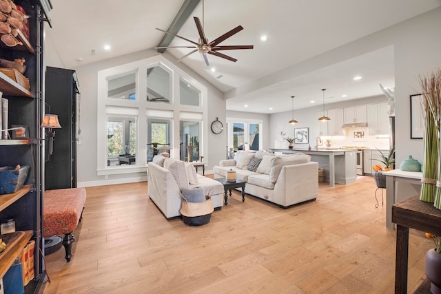 living room featuring vaulted ceiling with beams, light hardwood / wood-style floors, sink, and ceiling fan