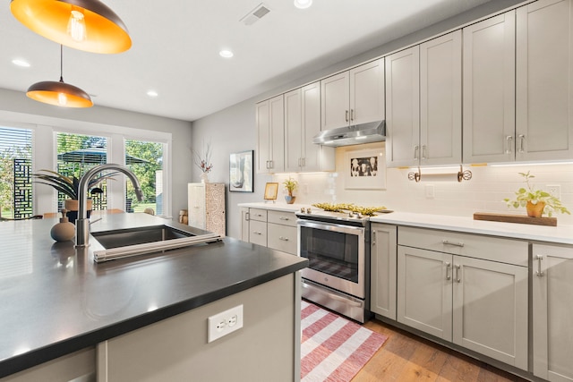 kitchen with hanging light fixtures, decorative backsplash, light hardwood / wood-style flooring, sink, and stainless steel electric range oven