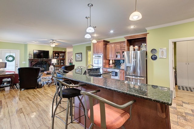 4200 S Rangeline Rd, Columbia, MO 65201 - kitchen featuring stainless steel appliances, crown molding, a ceiling fan, a kitchen bar, and brown cabinets
