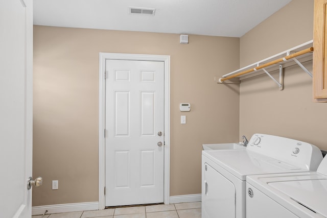 clothes washing area featuring baseboards, visible vents, washing machine and dryer, a sink, and light tile patterned flooring