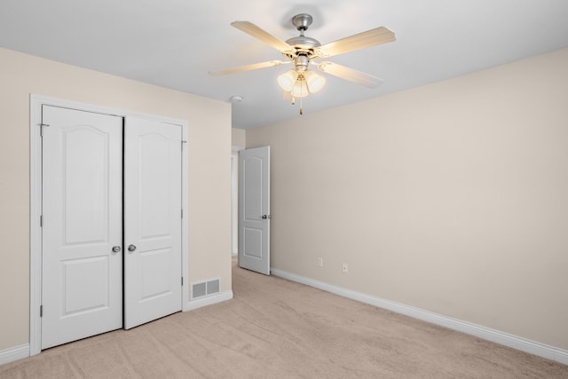 unfurnished bedroom featuring light carpet, a closet, visible vents, and baseboards