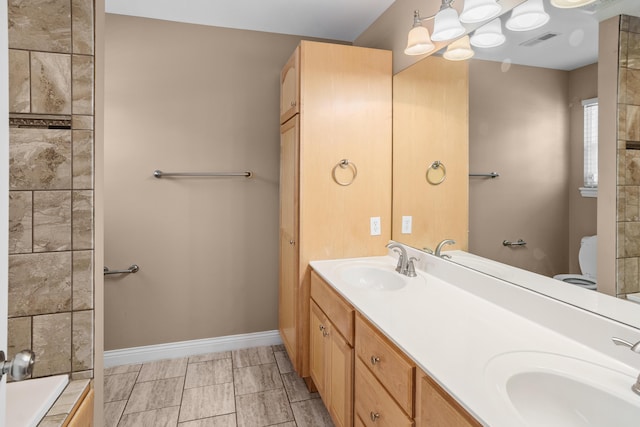 bathroom featuring toilet, visible vents, a sink, and baseboards