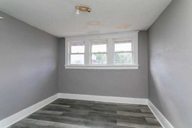 unfurnished room with a textured ceiling and dark hardwood / wood-style floors