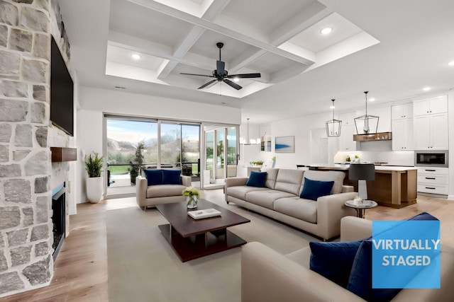 living room featuring coffered ceiling, a fireplace, light wood-type flooring, beam ceiling, and ceiling fan