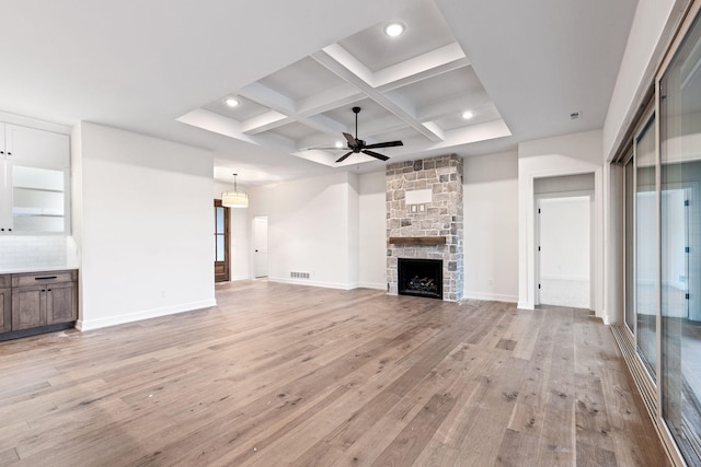 unfurnished living room featuring ceiling fan, light hardwood / wood-style floors, coffered ceiling, and a fireplace