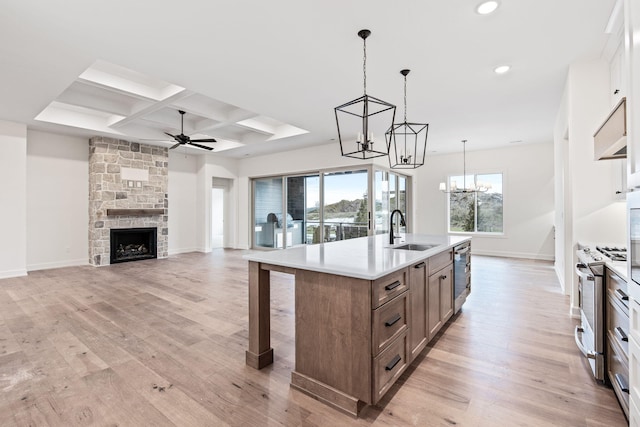 kitchen with stainless steel appliances, a center island with sink, light wood-type flooring, and sink