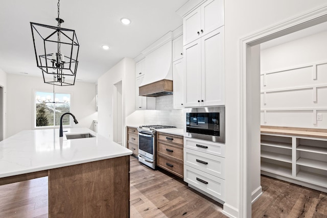 kitchen featuring a kitchen island with sink, sink, white cabinets, stainless steel appliances, and dark hardwood / wood-style flooring