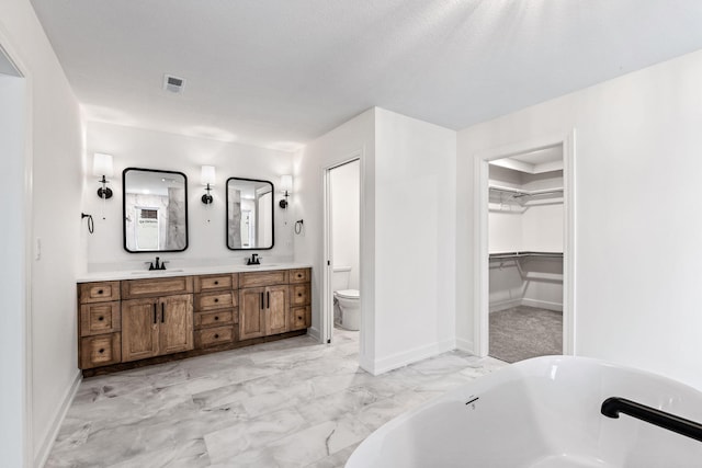 bathroom with a bath, a textured ceiling, vanity, and toilet