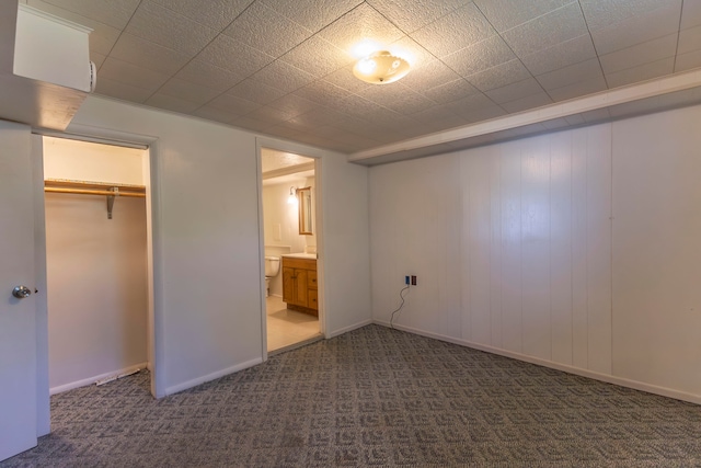 unfurnished bedroom featuring dark carpet, connected bathroom, and a closet