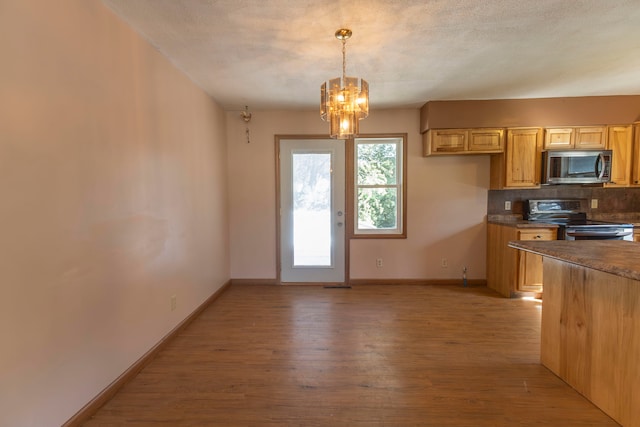 kitchen featuring decorative light fixtures, backsplash, black / electric stove, light brown cabinetry, and light hardwood / wood-style floors