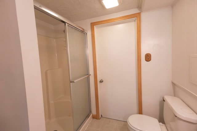 bathroom with a textured ceiling, a shower with shower door, and toilet