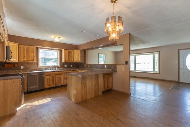 kitchen featuring decorative light fixtures, light hardwood / wood-style flooring, kitchen peninsula, and stainless steel dishwasher