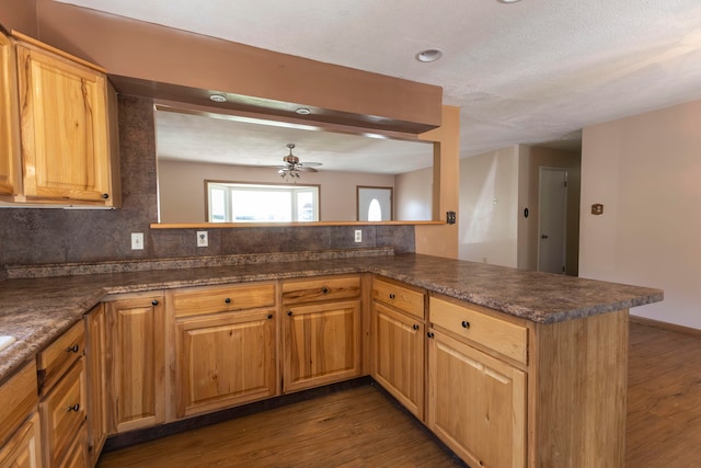 kitchen with decorative backsplash, kitchen peninsula, dark hardwood / wood-style floors, and ceiling fan