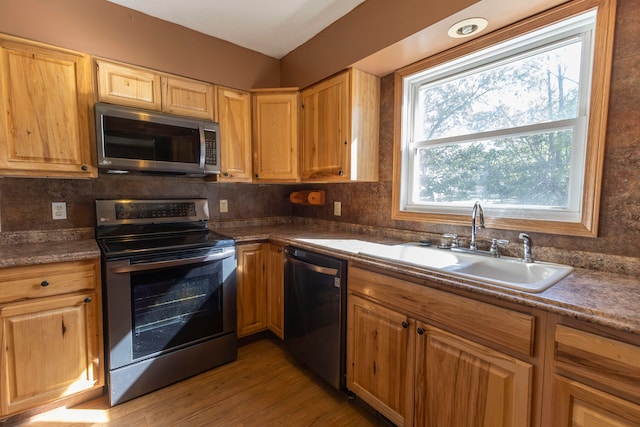 kitchen with stainless steel appliances, light wood-type flooring, sink, and decorative backsplash