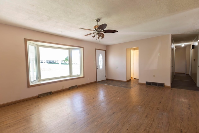 interior space with a textured ceiling, ceiling fan, and dark wood-type flooring