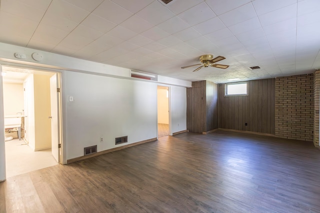 spare room featuring ceiling fan, wood walls, and hardwood / wood-style floors