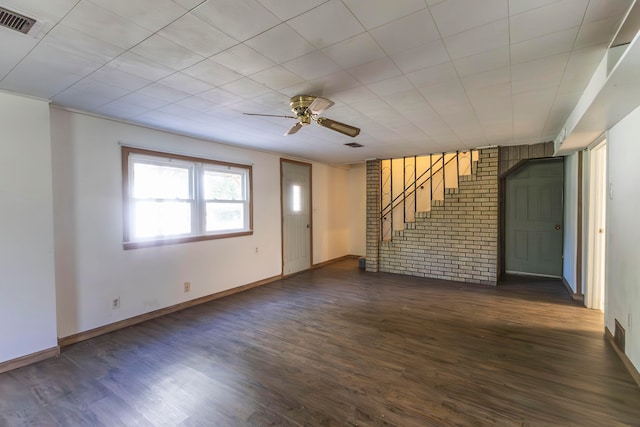 spare room featuring ceiling fan, brick wall, and dark wood-type flooring