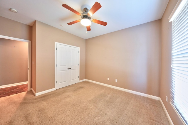 unfurnished bedroom featuring ceiling fan, a closet, and carpet