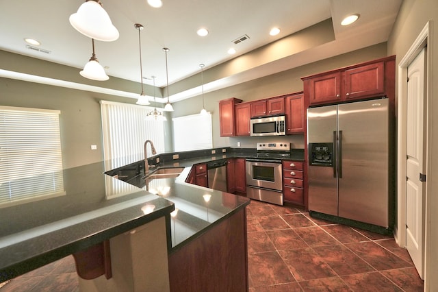 kitchen featuring pendant lighting, sink, an inviting chandelier, a raised ceiling, and appliances with stainless steel finishes