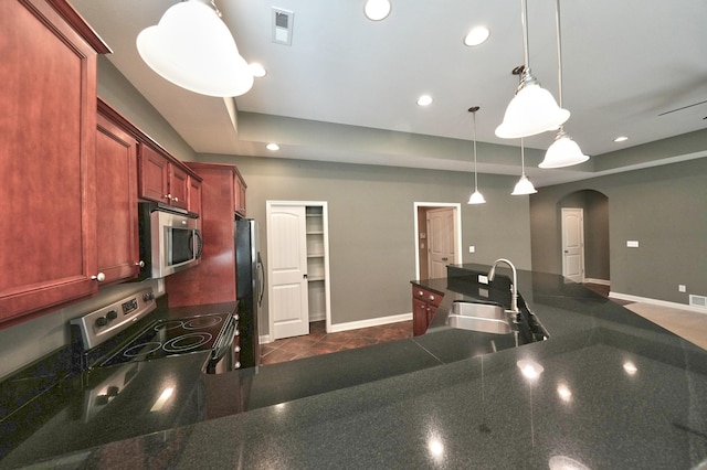 kitchen featuring appliances with stainless steel finishes, sink, dark tile patterned flooring, and decorative light fixtures