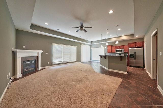 kitchen featuring a breakfast bar, a tile fireplace, a kitchen island, stainless steel appliances, and decorative light fixtures