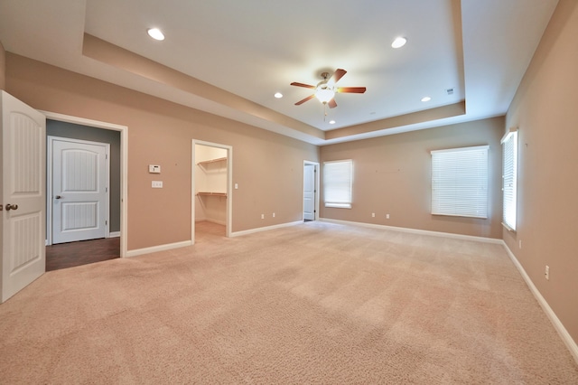 spare room with a raised ceiling, carpet flooring, and ceiling fan