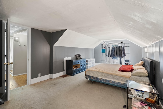 bedroom featuring light carpet, a textured ceiling, and vaulted ceiling