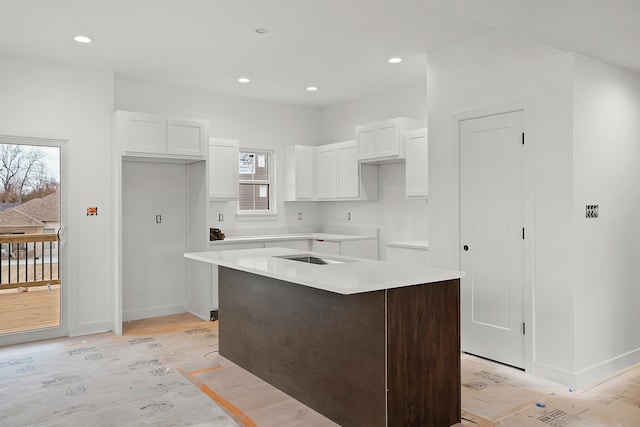 kitchen featuring a center island, sink, light hardwood / wood-style flooring, and white cabinets