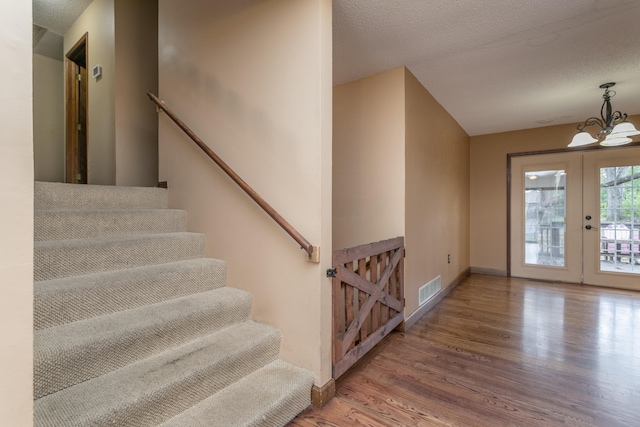 entrance foyer featuring a notable chandelier, a textured ceiling, hardwood / wood-style flooring, and french doors