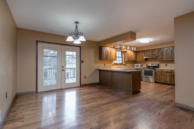 kitchen with dark hardwood / wood-style flooring, kitchen peninsula, stainless steel range with electric cooktop, and plenty of natural light