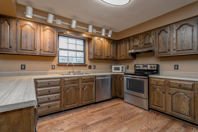 kitchen featuring a textured ceiling, sink, light hardwood / wood-style flooring, and appliances with stainless steel finishes