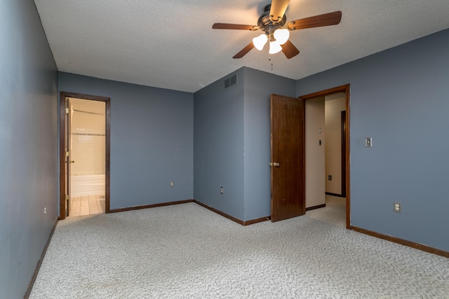 unfurnished bedroom with a textured ceiling, carpet, ensuite bath, and ceiling fan