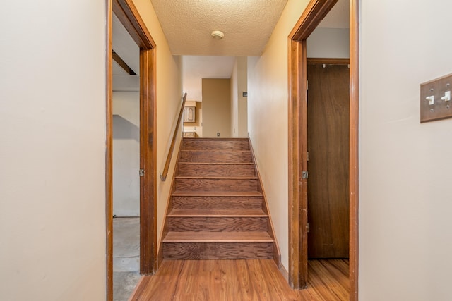 staircase featuring wood-type flooring and a textured ceiling