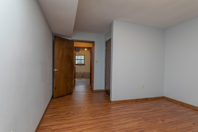 empty room with a textured ceiling and light hardwood / wood-style flooring