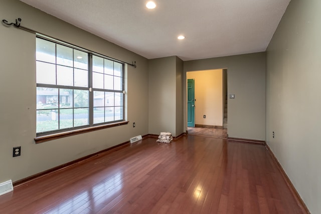 unfurnished room featuring hardwood / wood-style floors, a wealth of natural light, and a textured ceiling