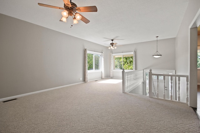 carpeted empty room with ceiling fan and a textured ceiling