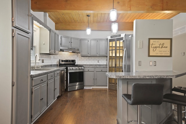 kitchen featuring hanging light fixtures, sink, appliances with stainless steel finishes, a breakfast bar area, and dark hardwood / wood-style flooring