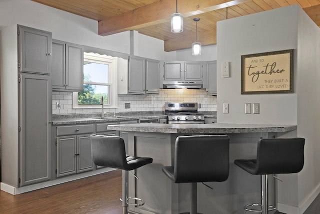 kitchen featuring beamed ceiling, wooden ceiling, a breakfast bar area, dark wood-type flooring, and stainless steel range with gas stovetop