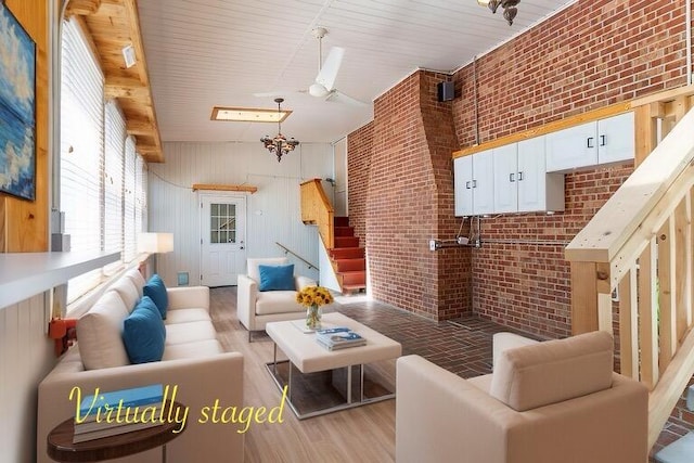 living room featuring wood walls, light hardwood / wood-style floors, brick wall, and a high ceiling